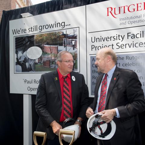 Jim Savage and Chris Molloy hold white hard hats and prepare to break ground at Paul Robeson Plaza