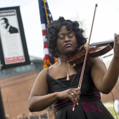 Postdoctoral associate Melanie Hill plays violin at the Paul Robeson Plaza dedication 