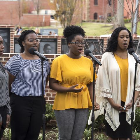 Four women from the Liberated Gospel Choir sing in front of Paul Robeson Plaza