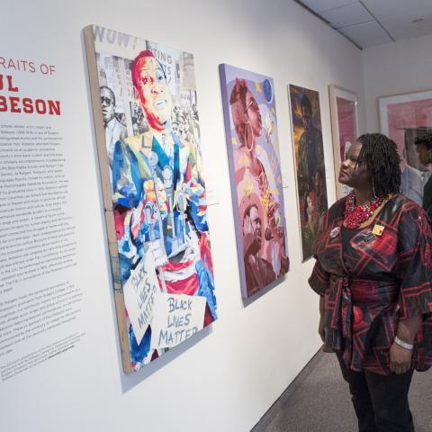 Simone Mack-Bright (RC'96) and other guests view artwork honoring Paul Robeson at reception following dedication ceremony for Paul Robeson Plaza 