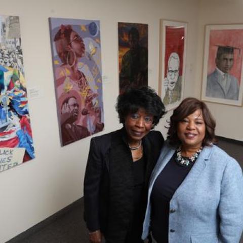Bernice Proctor Venable and Felicia McGinty stand in front of Paul Robeson portraits