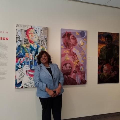 Felicia McGinty stands in front of Paul Robeson portraits