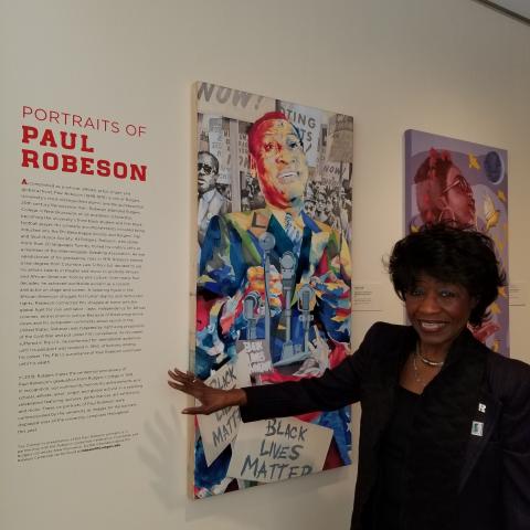 Bernice Proctor Venable stands in front of Paul Robeson portraits